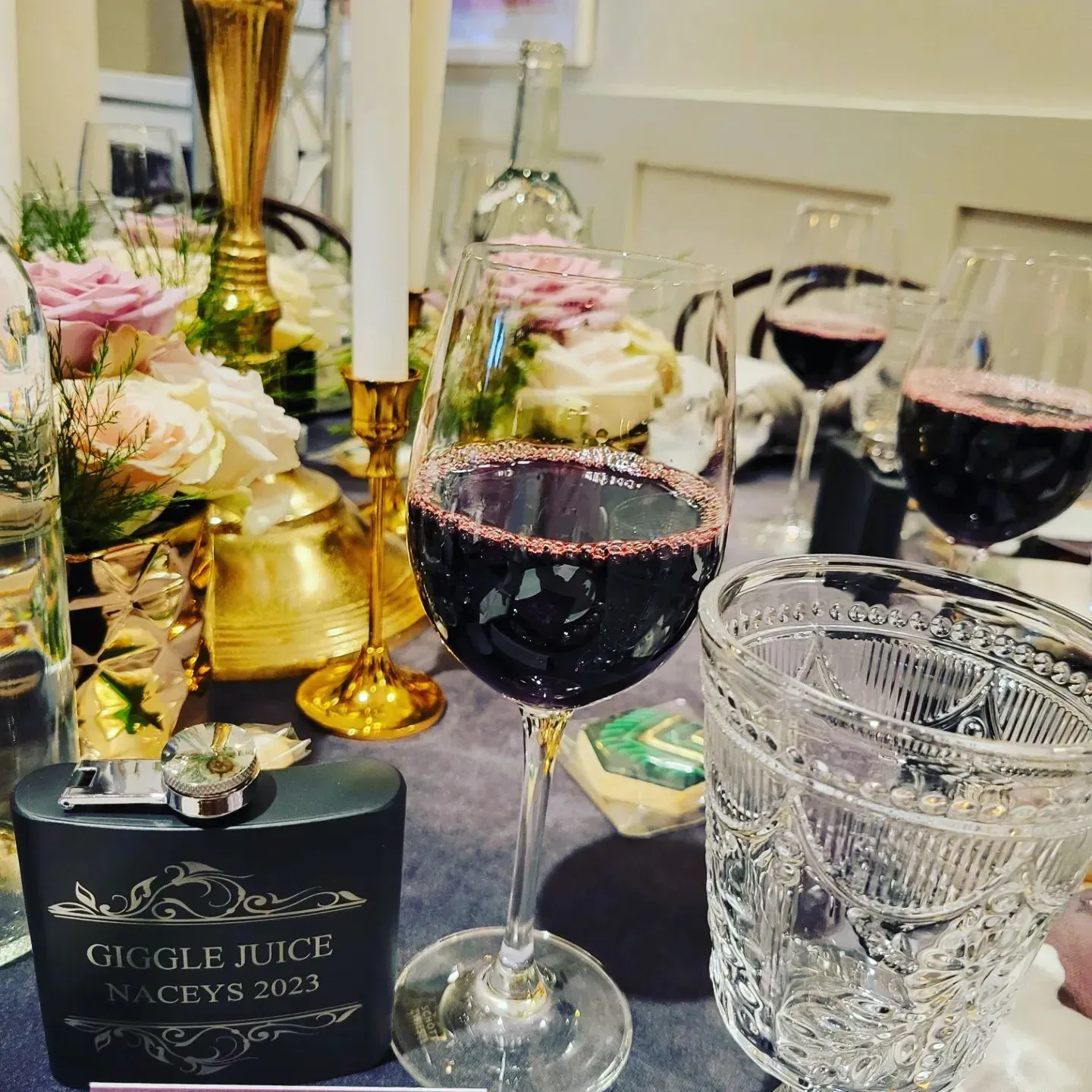 A bottle of gugle juice sits on a table next to a glass of wine