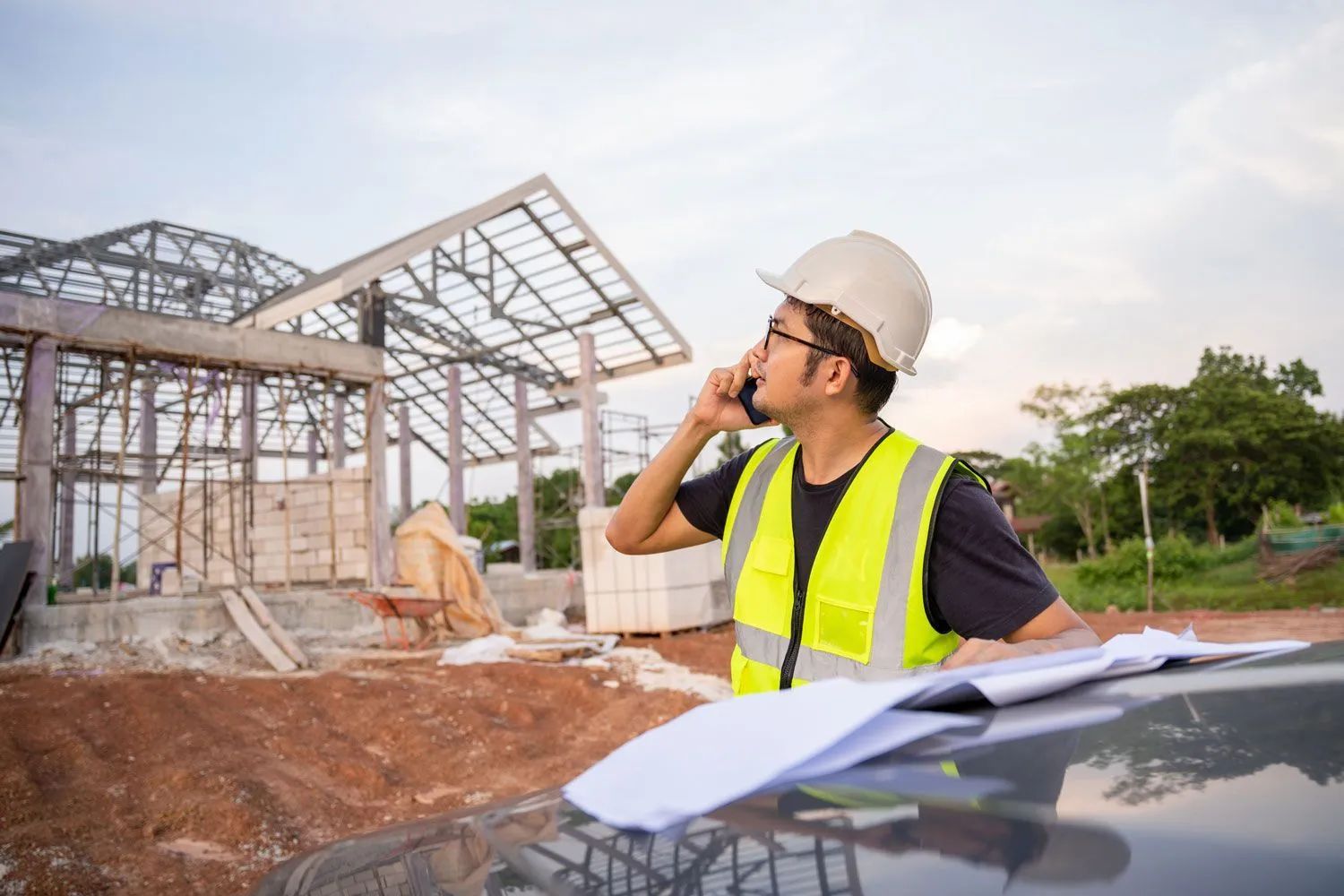 Construction worker in a hard hat and safety vest reviewing plans at a building site