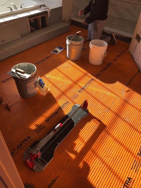 A tile cutter is sitting on a tile floor in a bathroom.