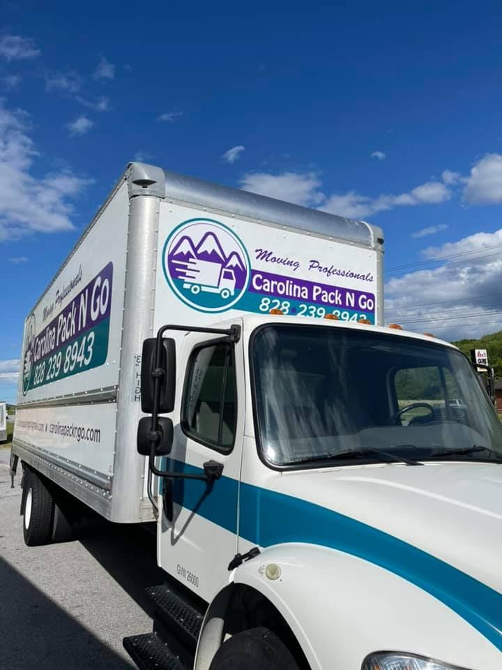 Moving truck from Carolina Pack N Go, white and blue, parked on a sunny day.