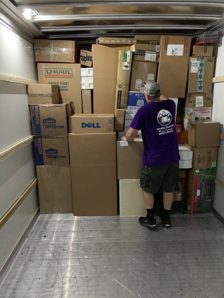 Man loading boxes into a moving truck. Boxes of various sizes and brands are stacked high, covering most of the space.