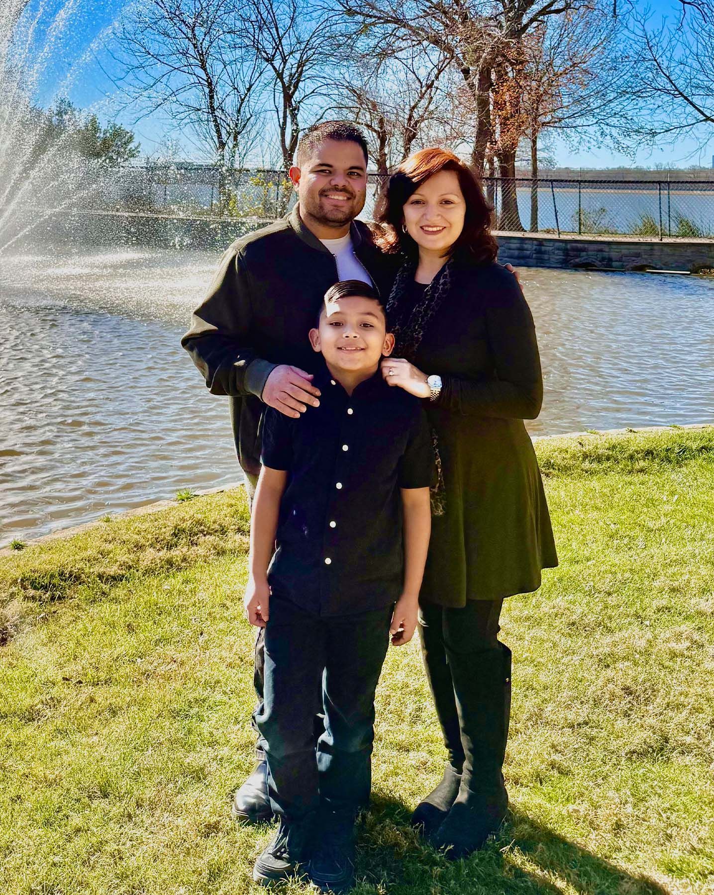 A family is posing for a picture in front of a lake.