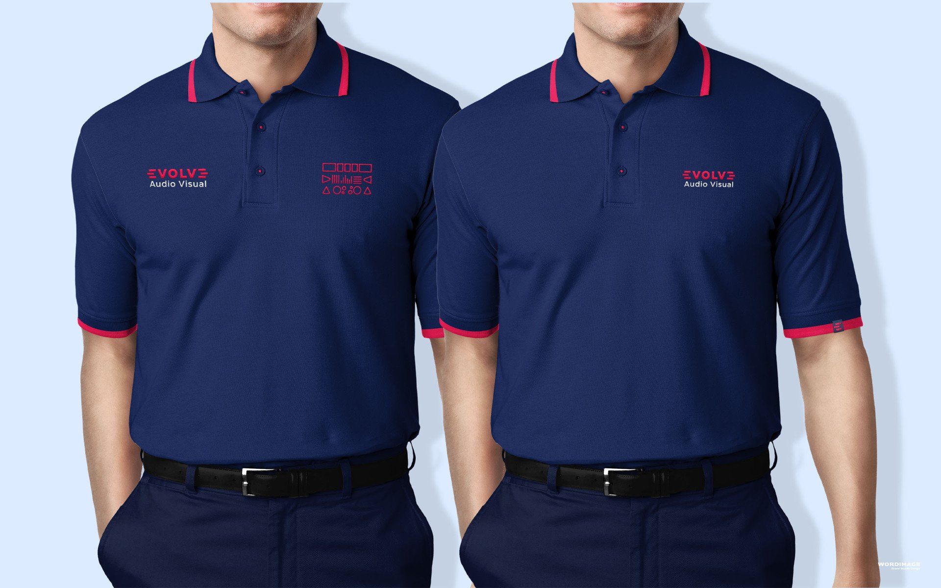 Two men wearing blue polo shirts with red trim are standing next to each other with their hands in their pockets.