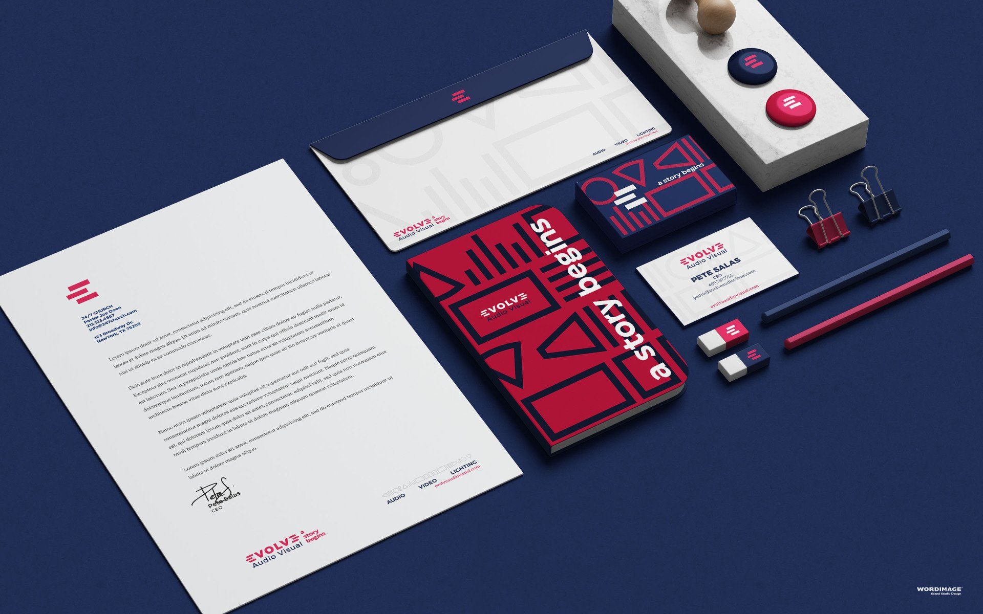 A mockup of business cards , envelopes , pencils , and a book on a blue surface.