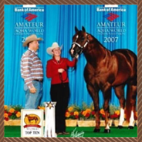 Woman and cowboy pose with a horse at an amateur world show backdrop with blue banners.