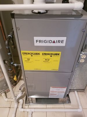 A frigidaire air conditioner is sitting on top of a tiled floor in a basement.