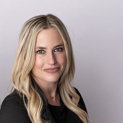 A woman with blonde hair is wearing a black shirt and smiling for the camera.