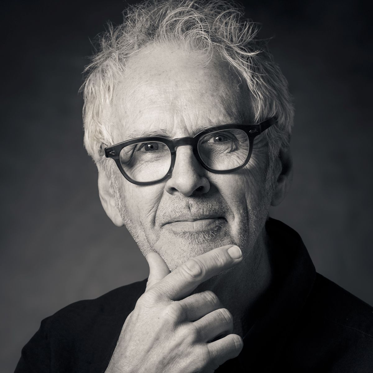 Man in glasses touches his chin, contemplating. Black and white portrait.