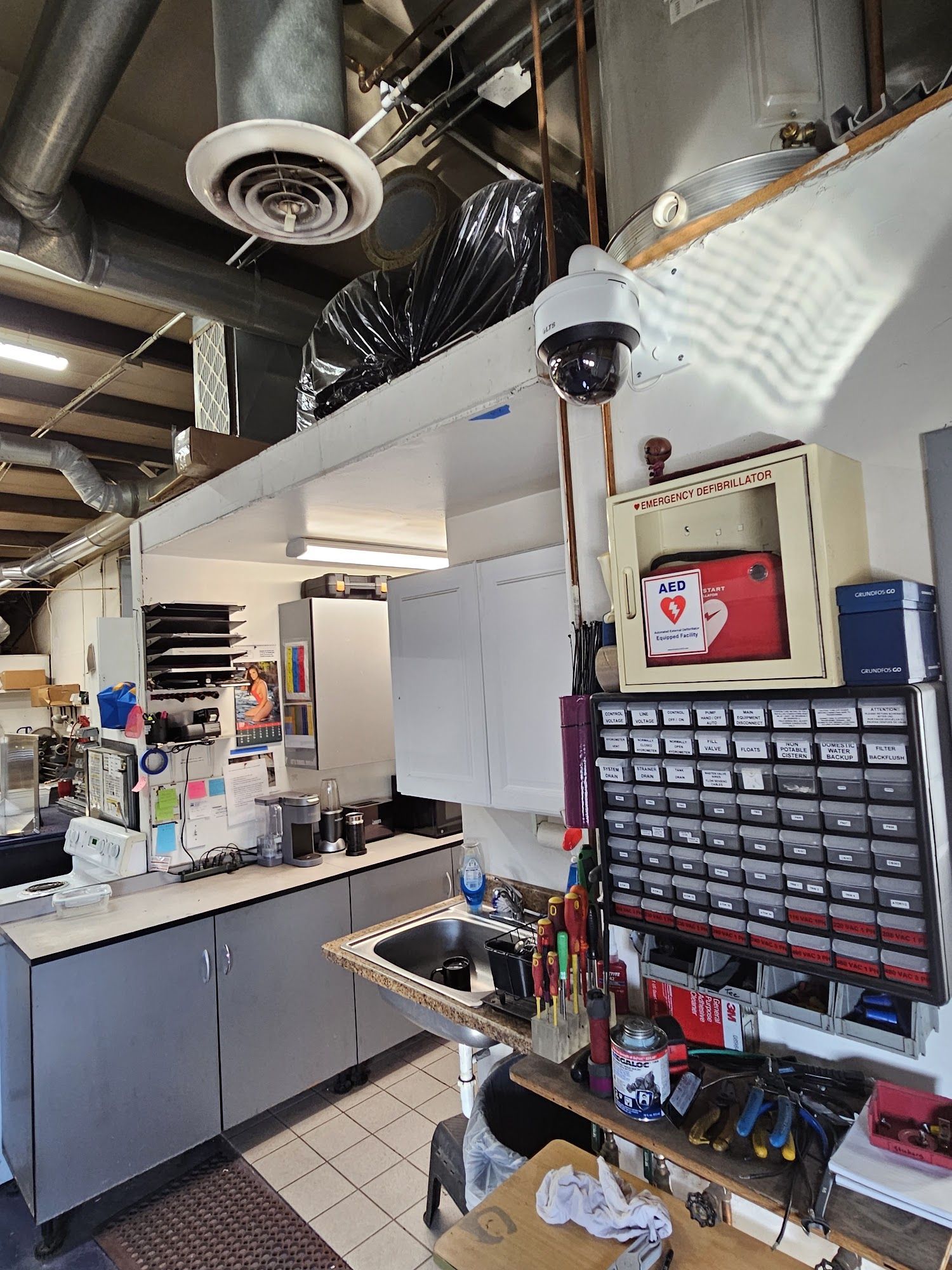 Workshop interior with cabinets, sink, tools, and a security camera mounted overhead.