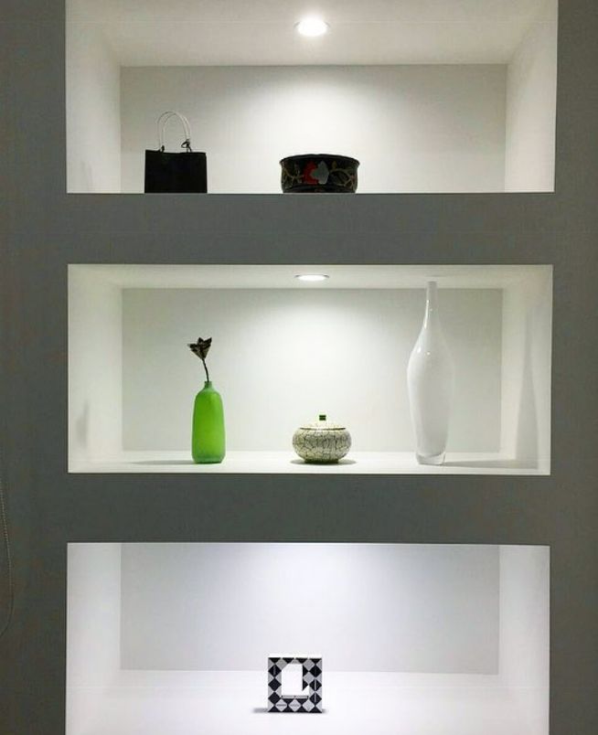A shelf with a green vase and a white vase on it
