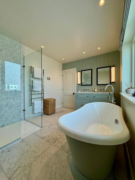 Modern bathroom with glass shower, freestanding tub, vanity, and tiled floor