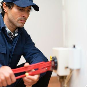 A man is fixing a water heater with a wrench.