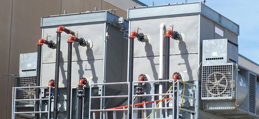 A row of cooling towers are sitting outside of a building.