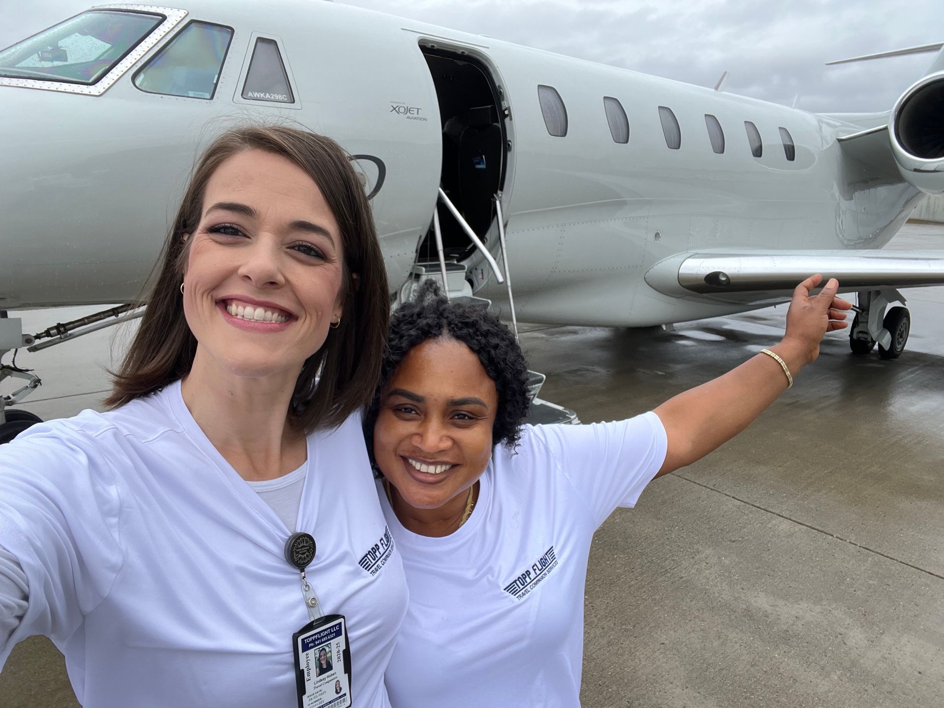 Two women are posing for a selfie in front of an airplane.