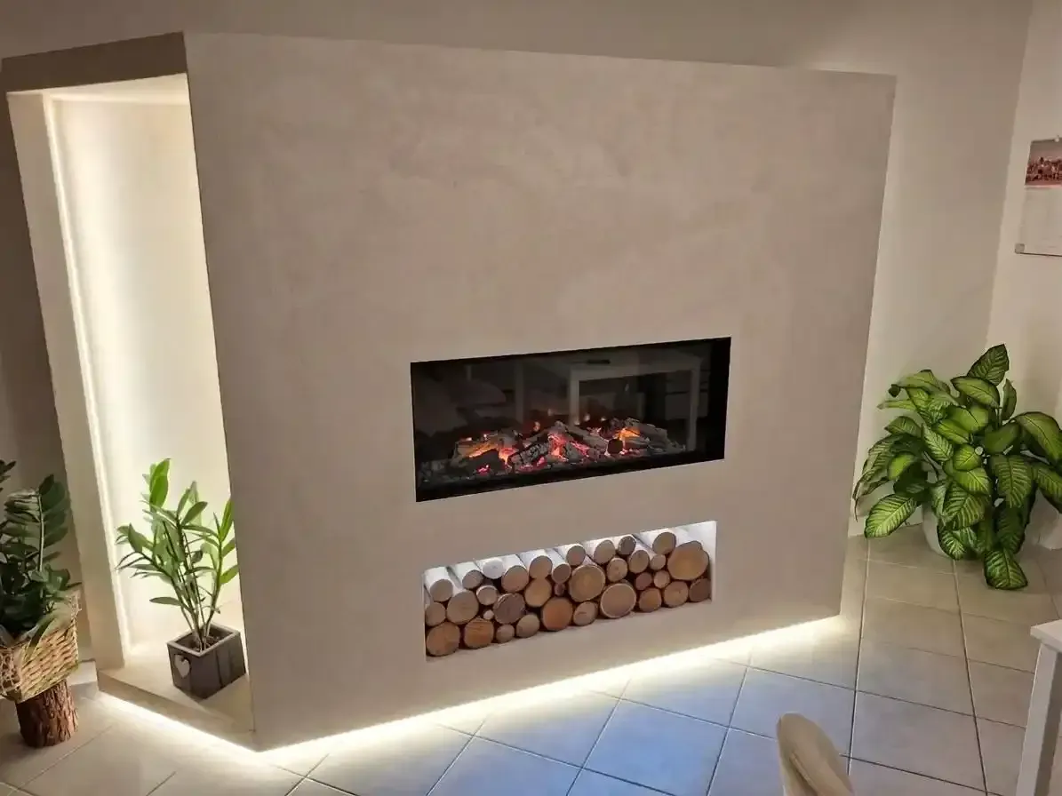 Donna che cucina su una stufa in maiolica rossa in una cucina luminosa con pavimenti in legno.