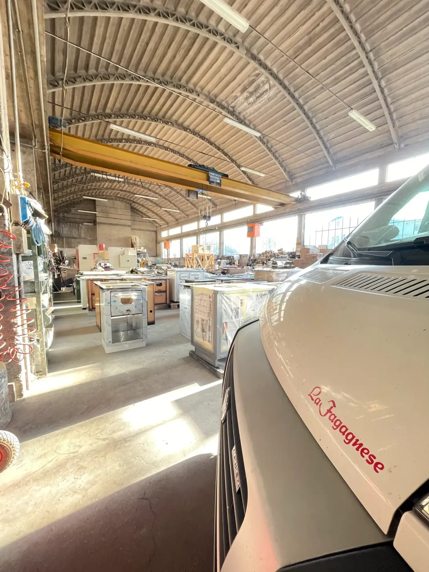 All'interno di un'officina con una gru, si intravede parzialmente un furgone chiaro, forse della Fragnese.