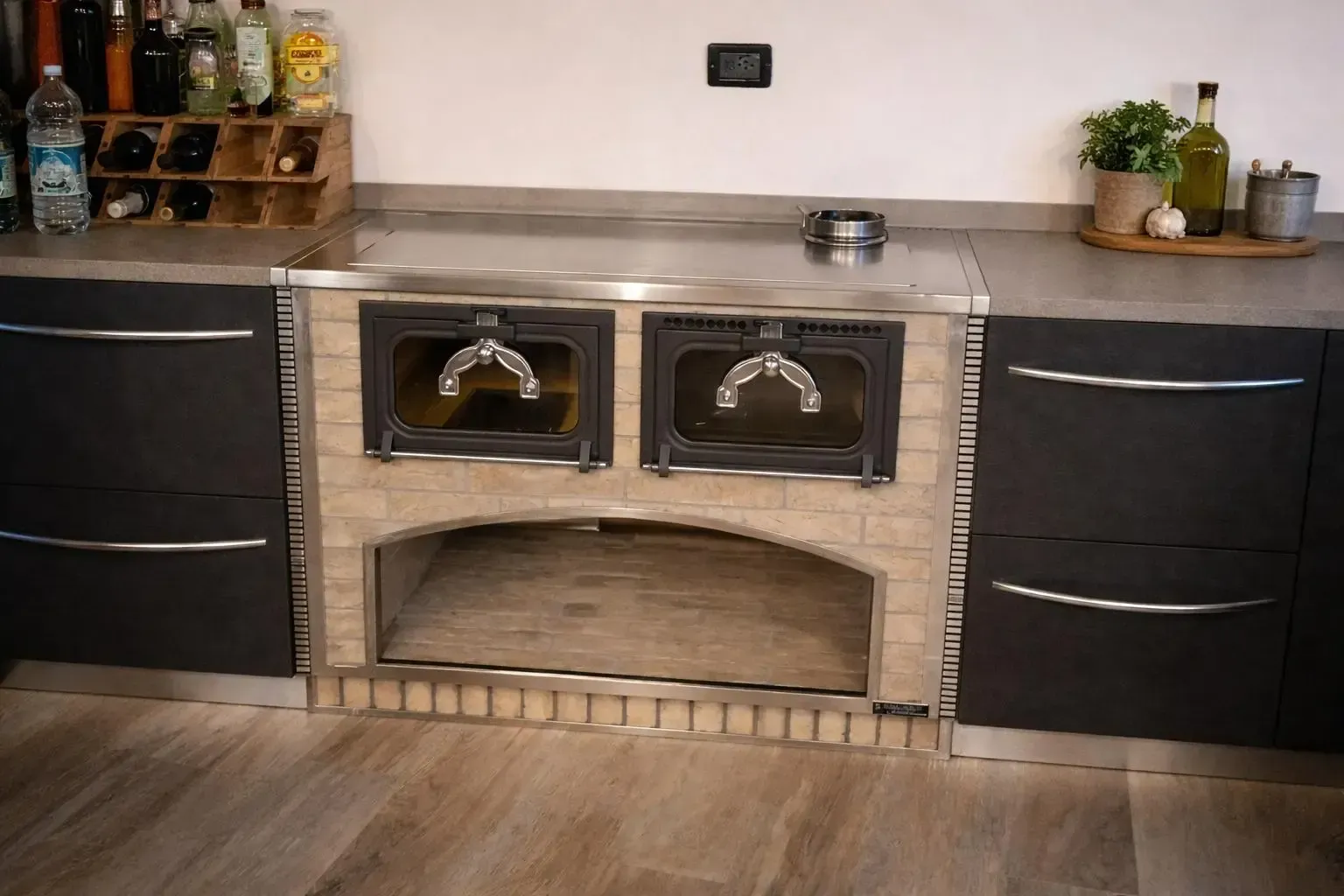 Forno in mattoni con due scomparti con porta in vetro, integrato nei mobili da cucina neri.