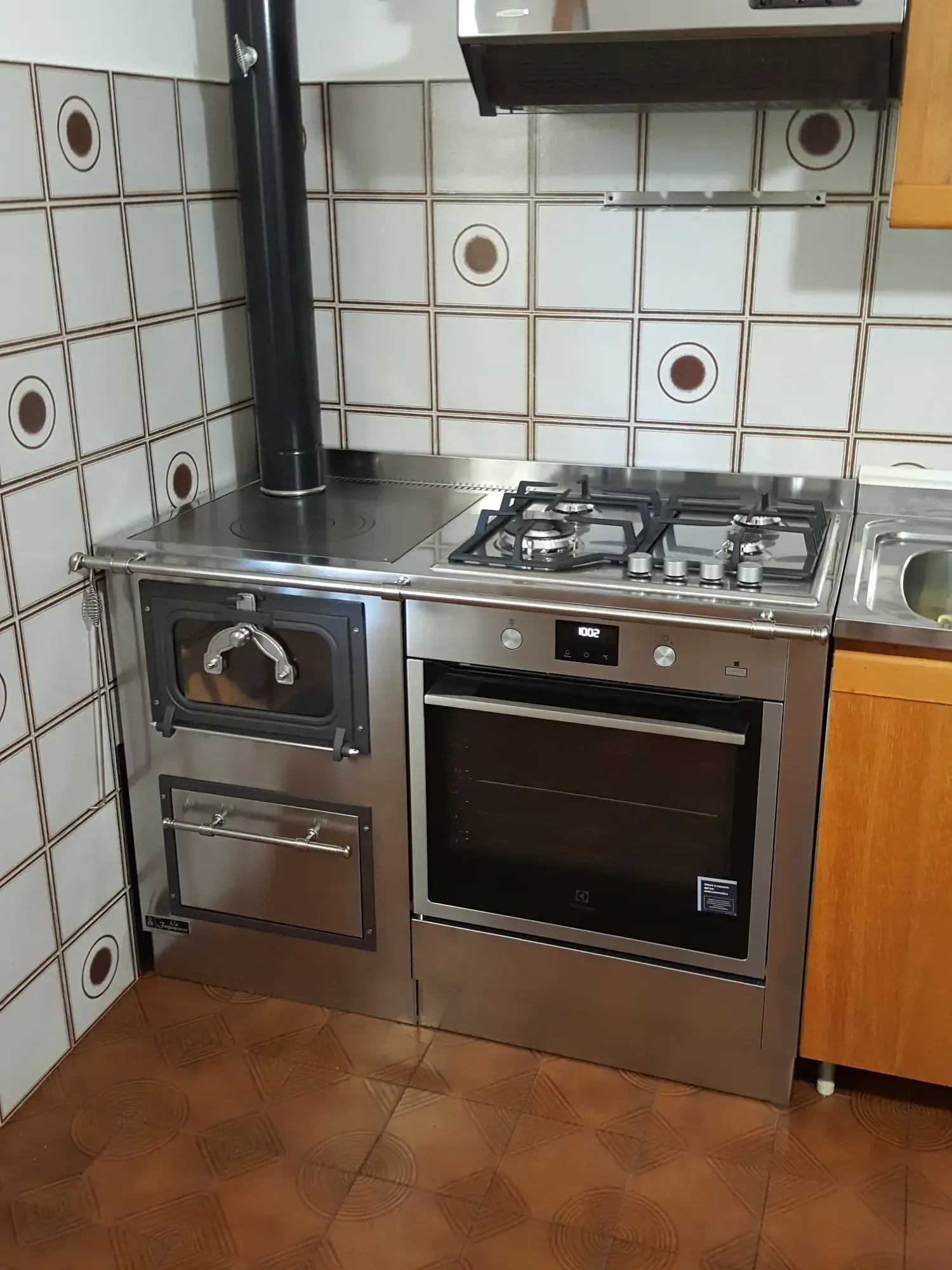 Cucina con piano cottura in acciaio inox, forno e pareti piastrellate.