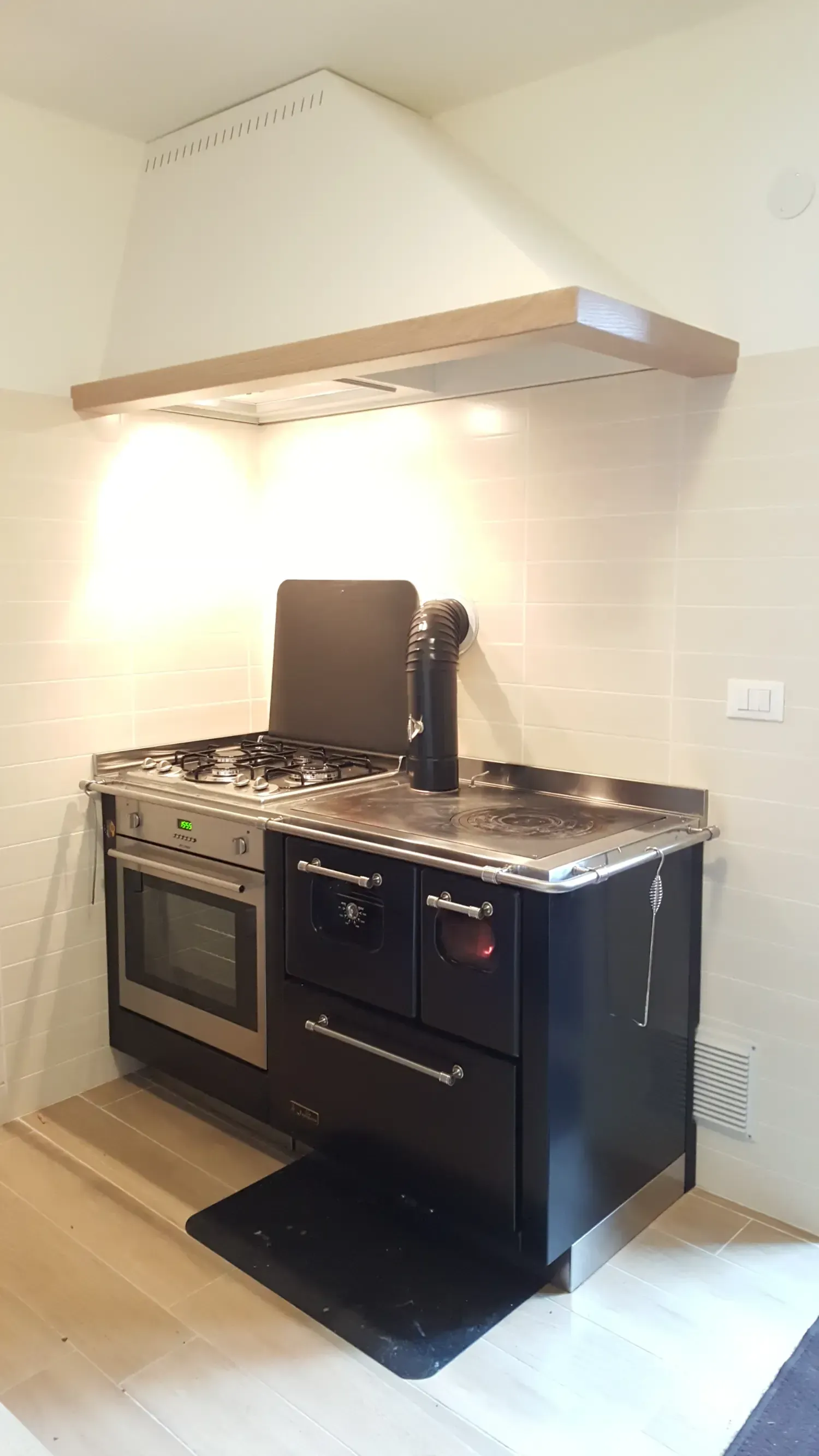 Cucina con piano cottura in acciaio inox e nero, forno, piano cottura e cappa.