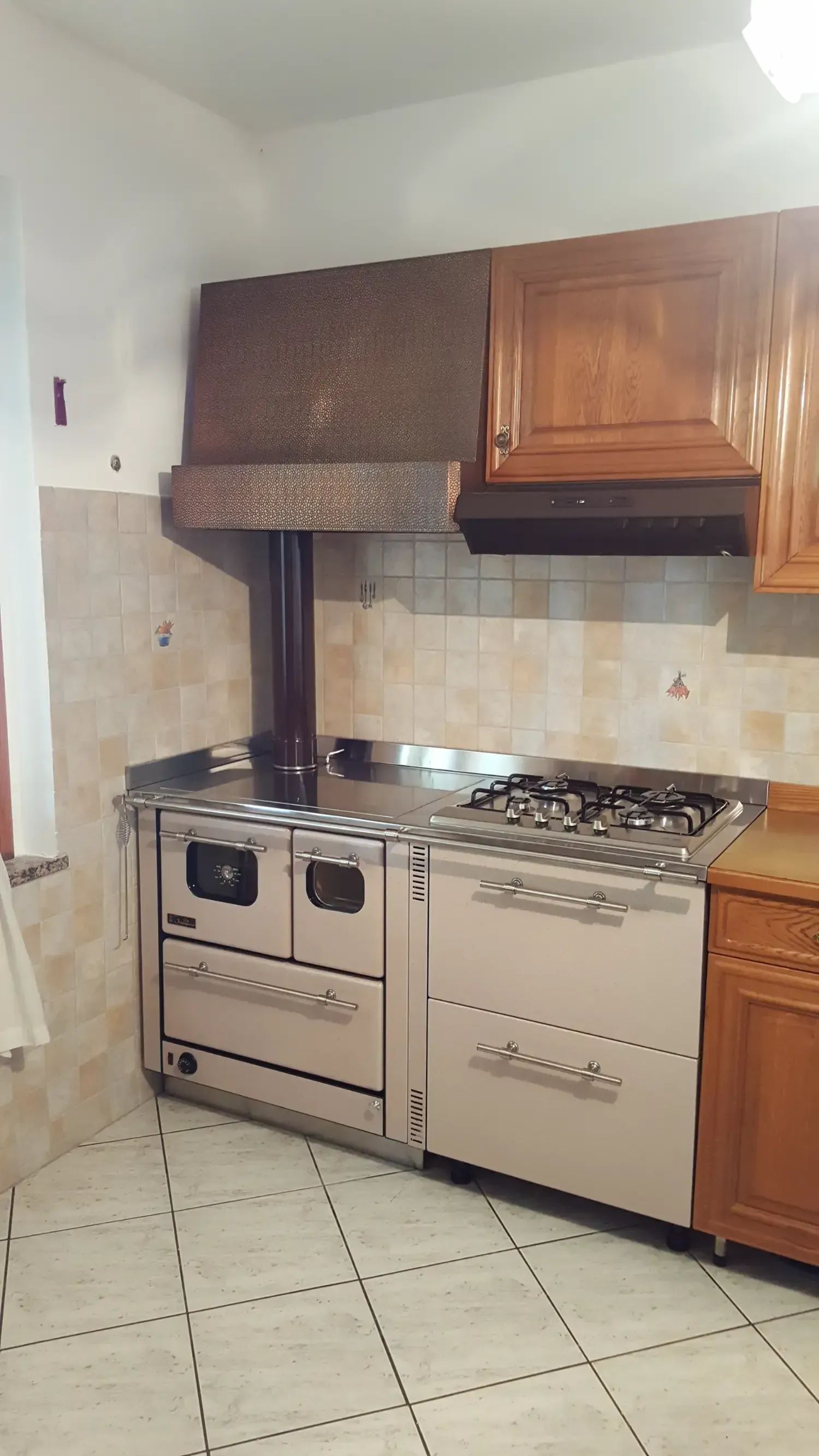 Cucina in acciaio inox con due forni, piano cottura a gas e cappa aspirante sopraelevata.