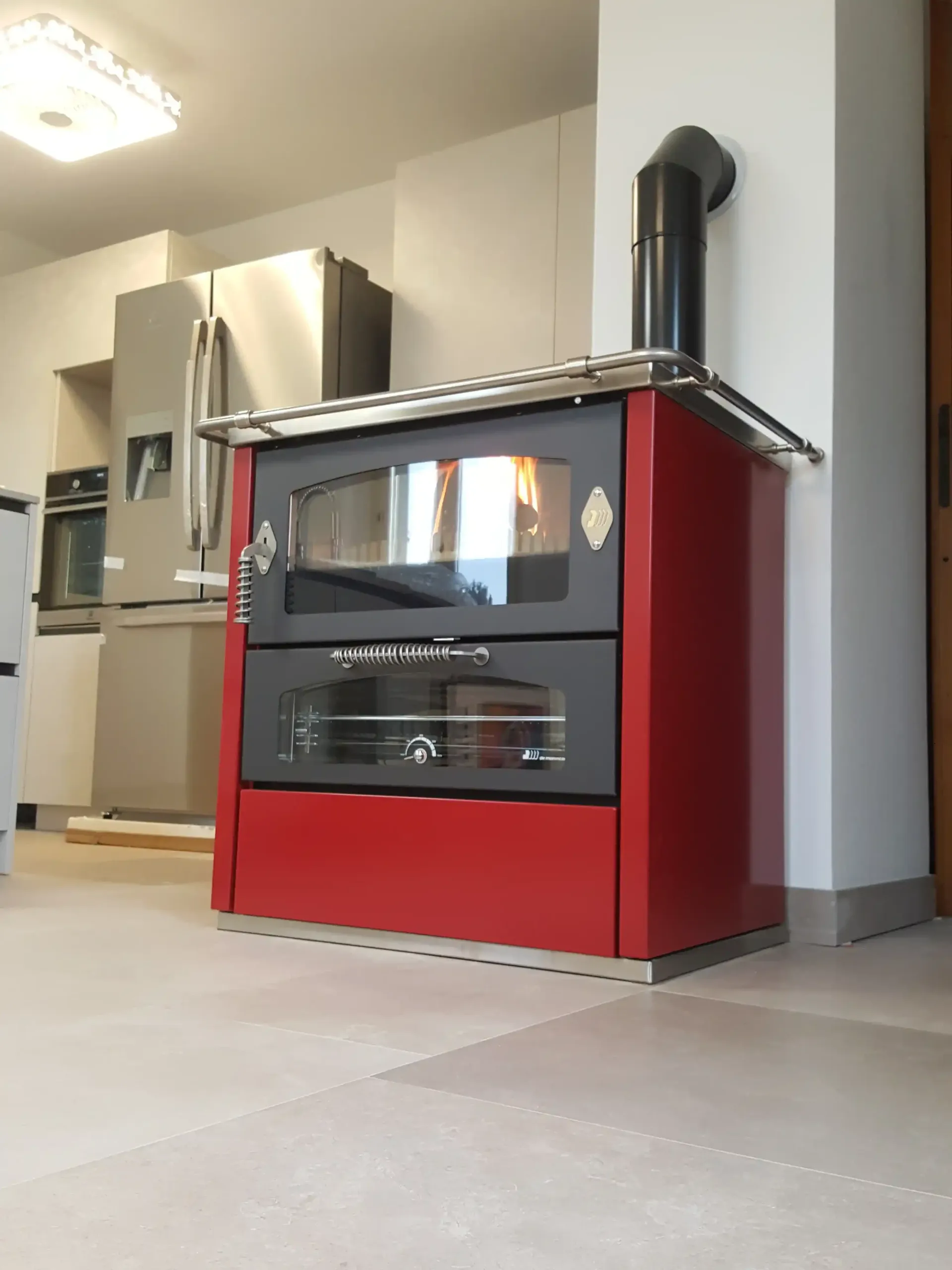 Stufa a legna rossa con sportelli neri in cucina, finiture in acciaio inossidabile, camino.