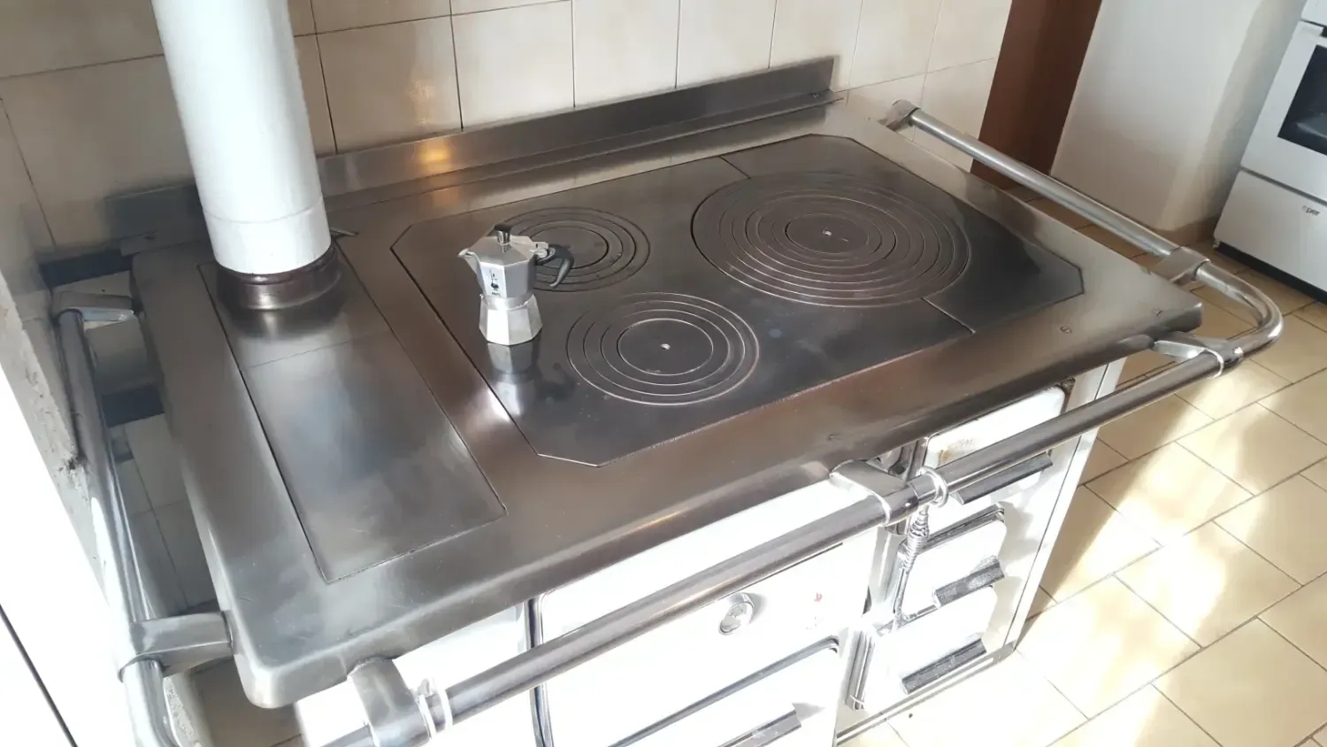 Una cucina con fornelli multipli, cassetti e una canna fumaria bianca in acciaio inox.