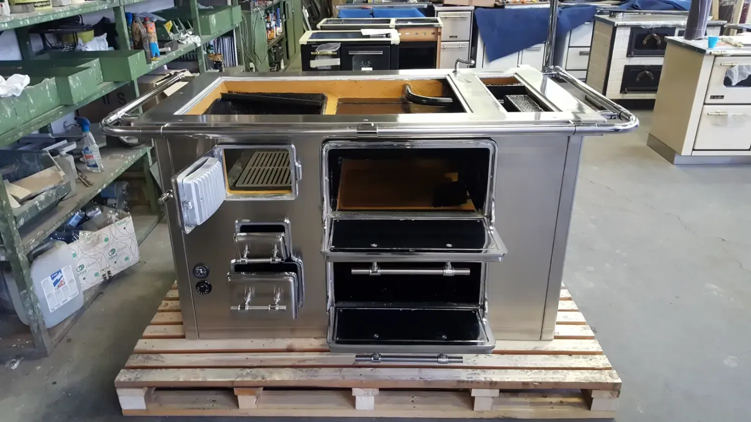 Cucina in acciaio inox con più forni e piani cottura, appoggiata su un pallet.