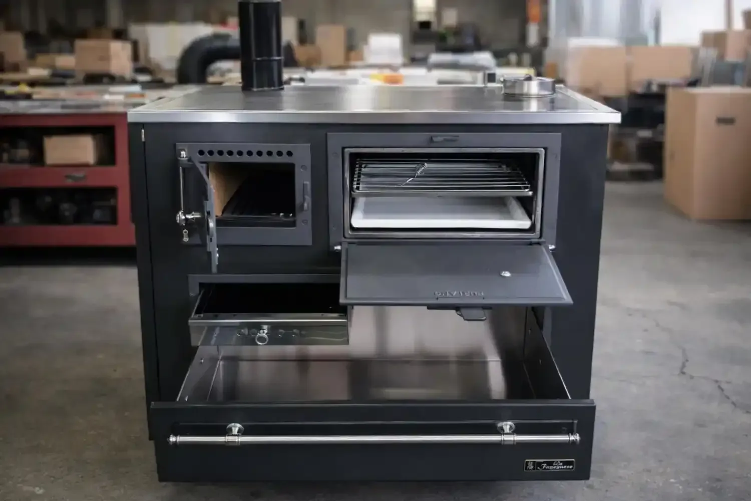 Cucina a legna nera con forno e cassetto portaoggetti.