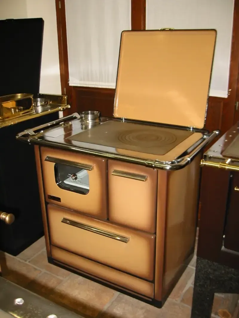 Stufa da cucina a legna d'epoca color marrone chiaro e marrone con coperchio aperto e sportello del forno.
