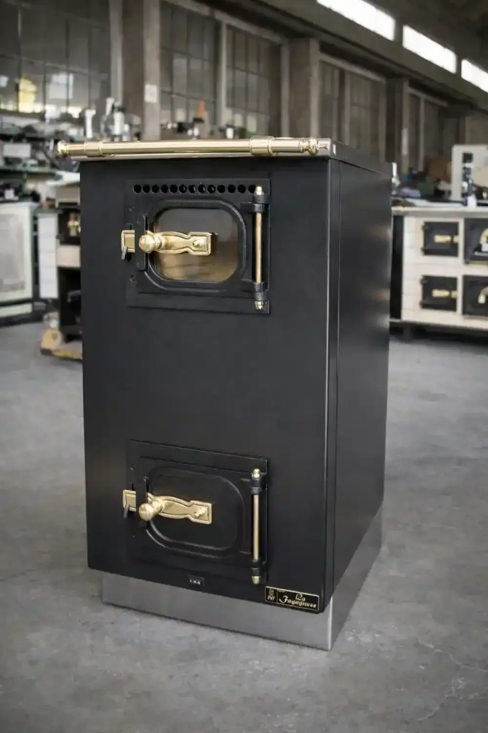 Forno da cucina nero e oro con due porte, base in acciaio inox, in un'officina.