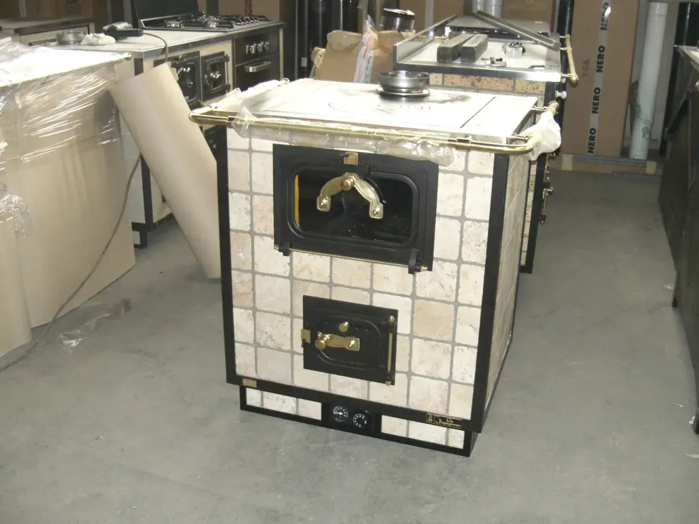 Forno rivestito in piastrelle con porta e camino neri, in un magazzino.