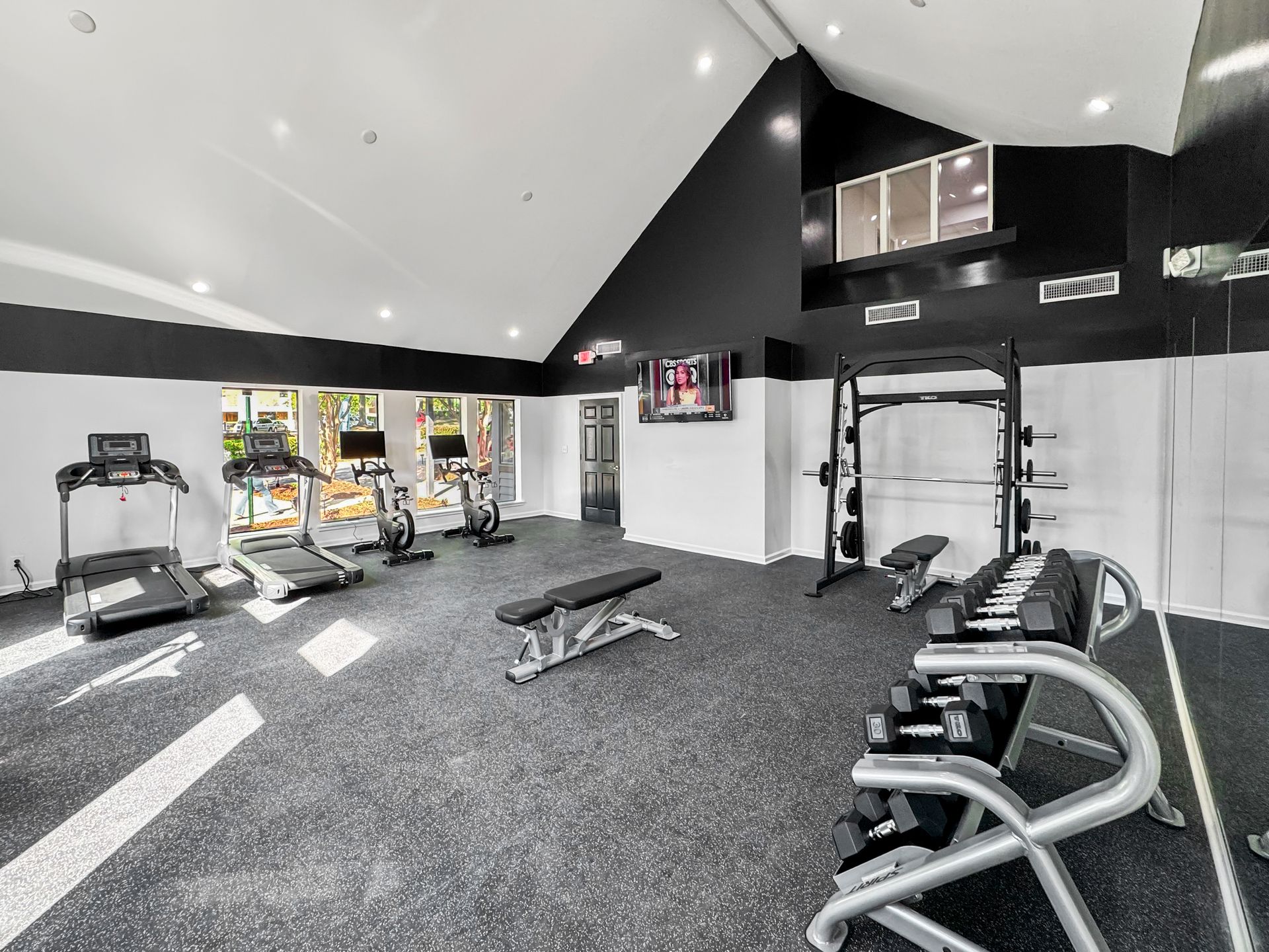Modern gym with treadmills, weights, and exercise benches in a black-and-white room