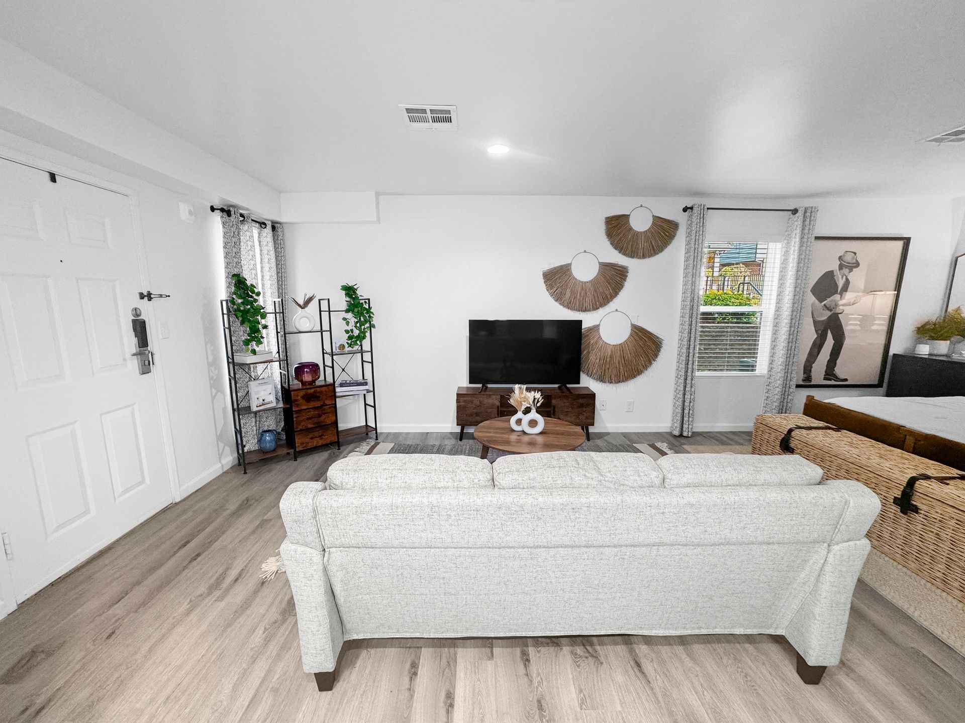 Bright living room with white sofas, TV, wall decor, and large sliding glass doors