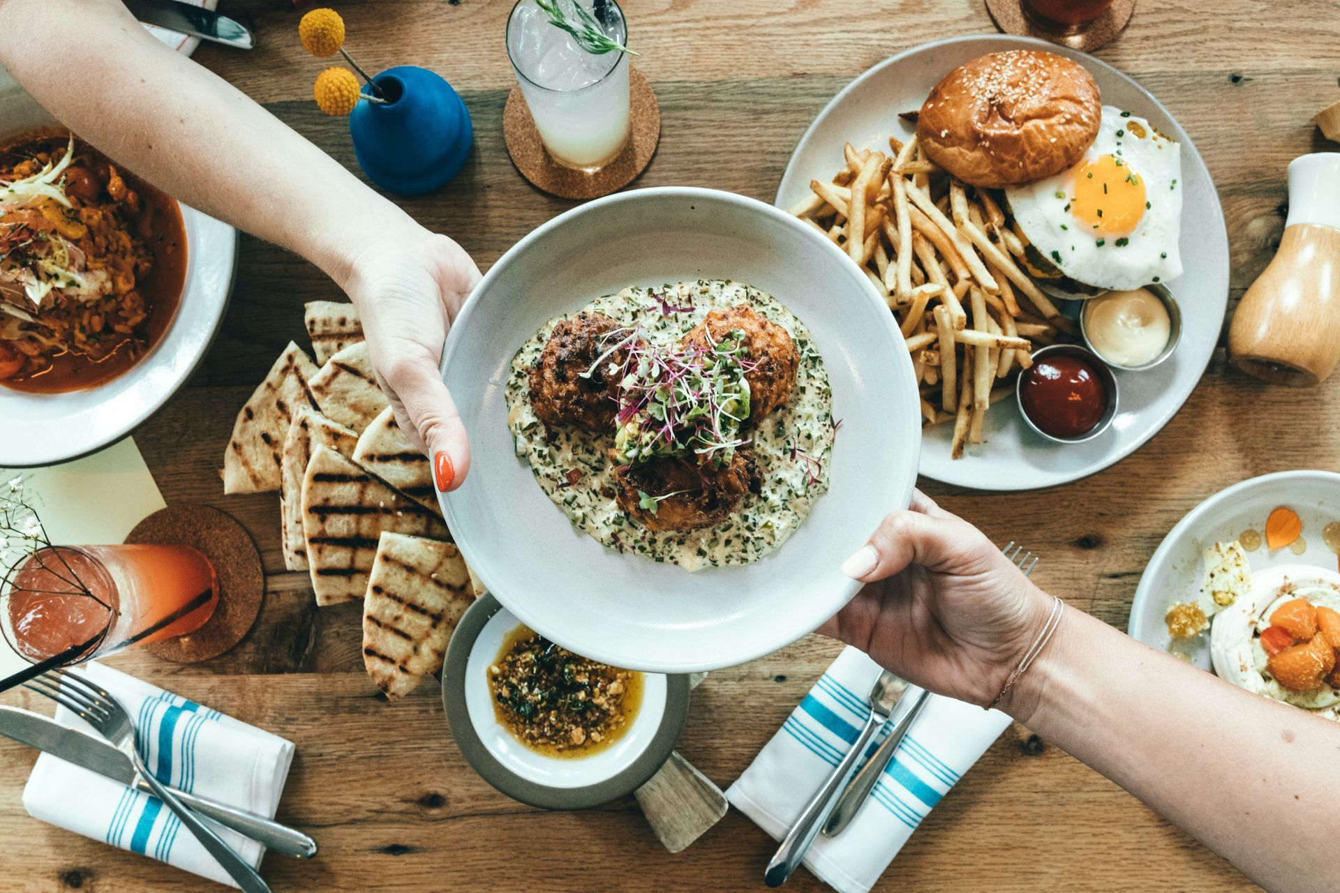 Overhead view of hands sharing a meal at a local Raleigh restaurant