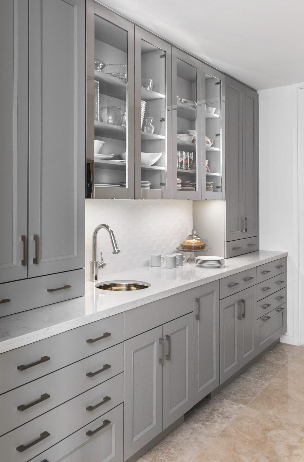 Elegant gray kitchen with glass-front cabinets, white countertop, and built-in sink.