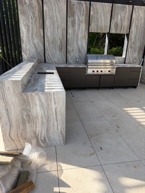 Outdoor patio with stone counters, built-in grill, and wood privacy wall