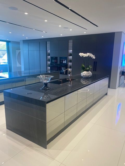 Modern luxury kitchen with glossy black island, white floors, and orchid decor