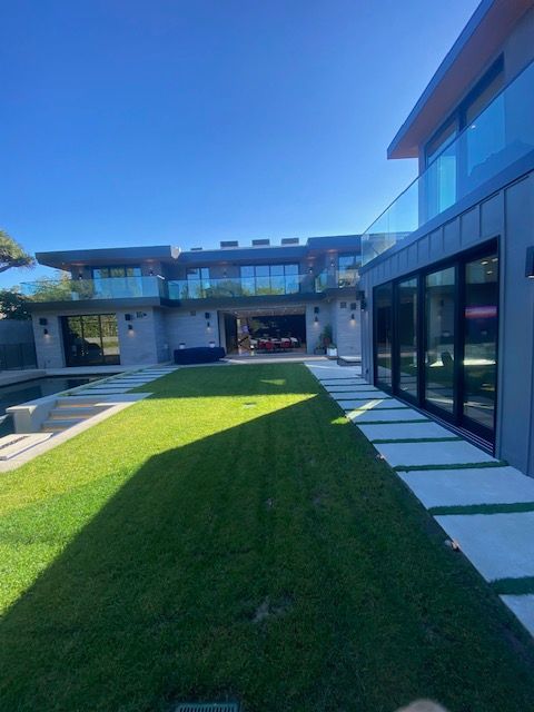 Modern courtyard with green lawn, glass building, and a blue sky