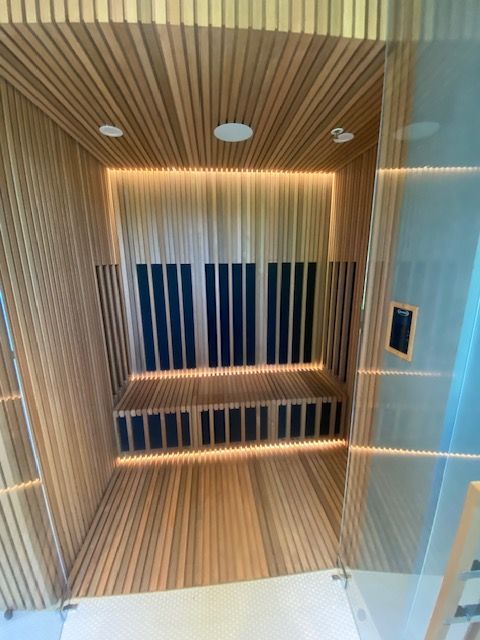 Modern wood-paneled shower or sauna stall with built-in bench and vertical slatted walls