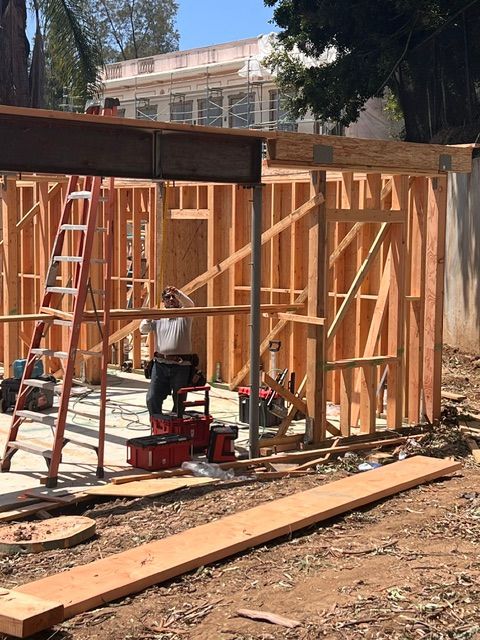 Wood-frame house under construction with lumber, ladders, and tools on site