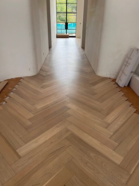 Hallway with light herringbone wood flooring leading to a glass door and garden view
