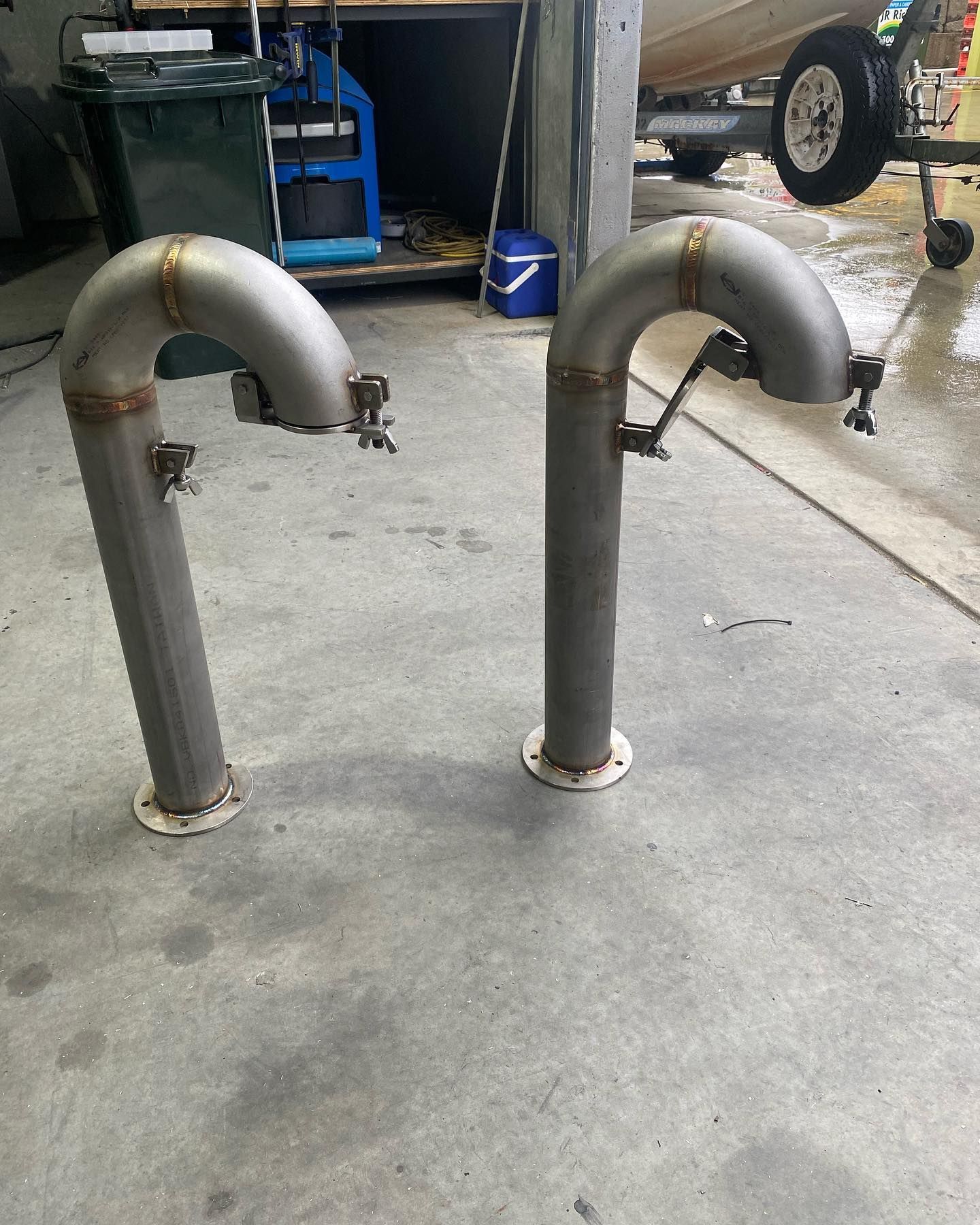 Two Metal U-Shaped Pipes Standing in A Wet Garage Floor Beside a Parked Vehicle — EB Metalworks in Somersby, NSW