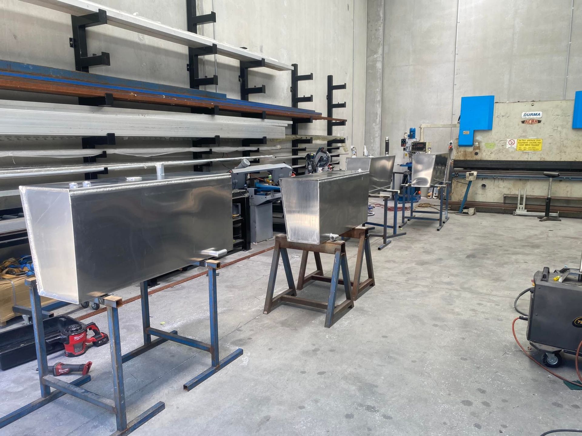 Industrial Workshop with Metal Panels on Stands, Tools, and Shelves Along the Wall — EB Metalworks in Somersby, NSW