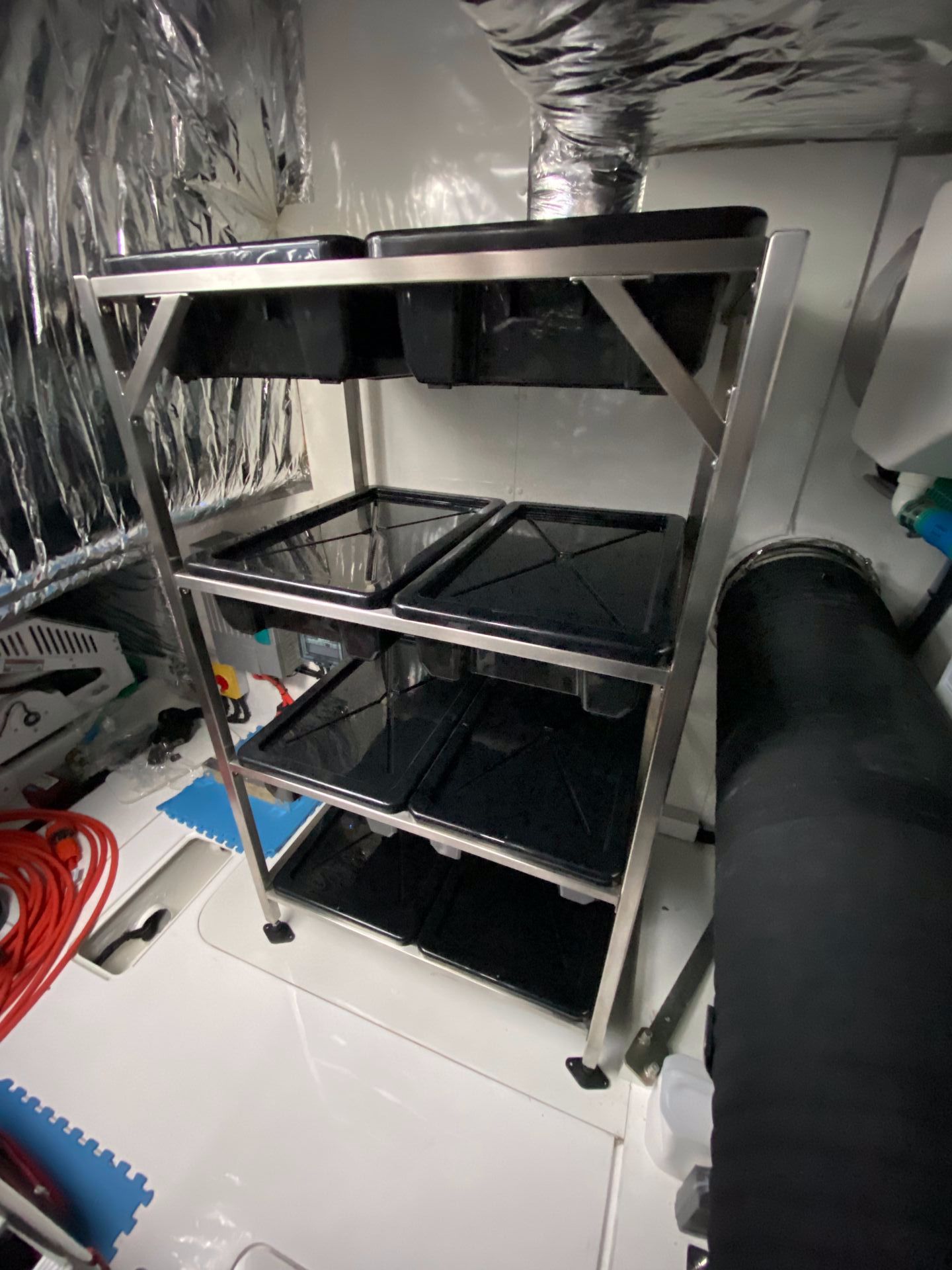 A Stainless Steel Shelf With Black Trays on It in a Room — EB Metalworks in Somersby, NSW