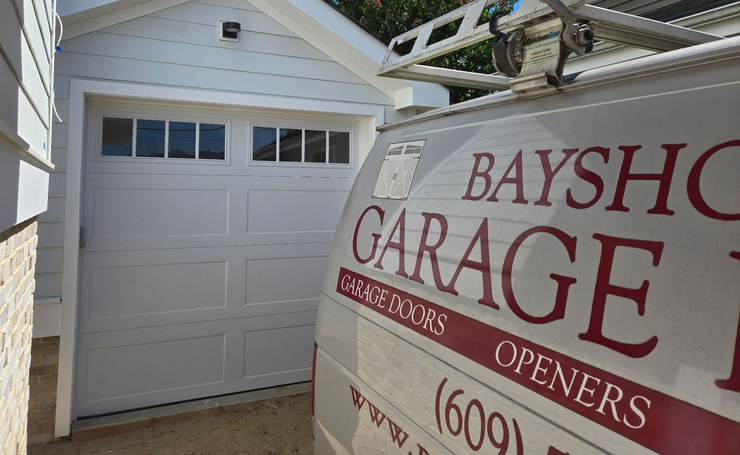 A service van for Bayshore Garage Doors parked in front of a white garage door with windows.