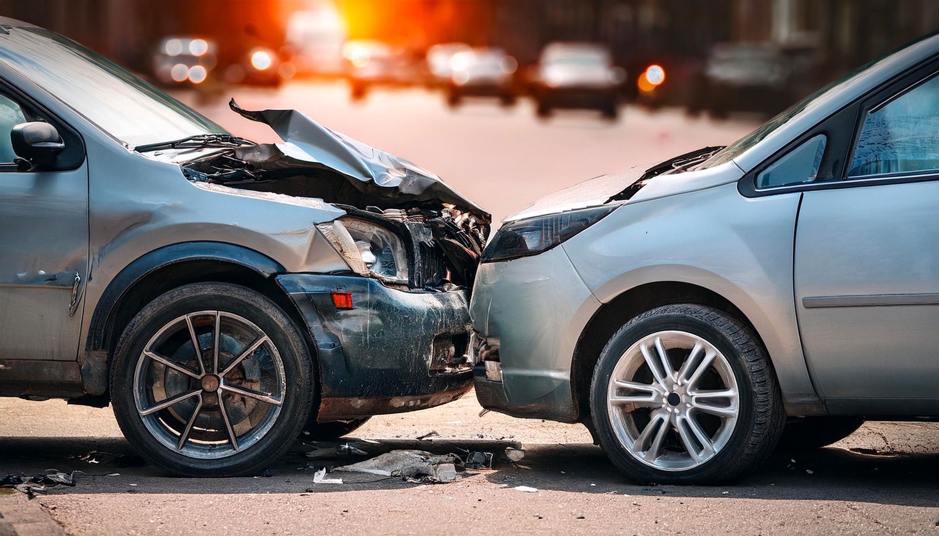 Two cars in a head-on collision on a city street, showing significant front-end damage