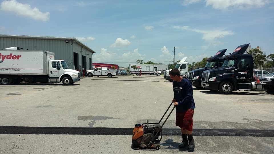 A man is using a machine in a parking lot in front of a truck that says ryder