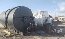 A Large Black Tank is Sitting on Top of a Dirt Field