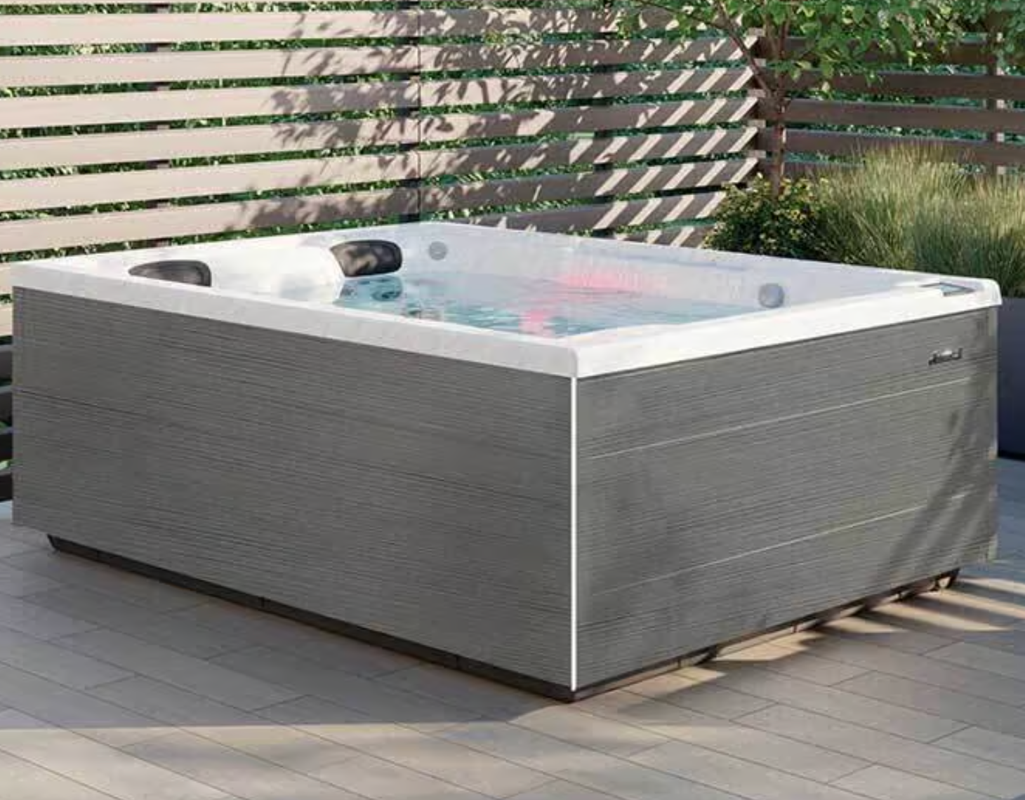 Un bain à remous est installé sur une terrasse à côté d'une piscine.