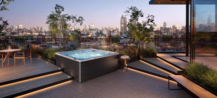 Un bain à remous blanc est installé sur une terrasse avec vue sur maison.